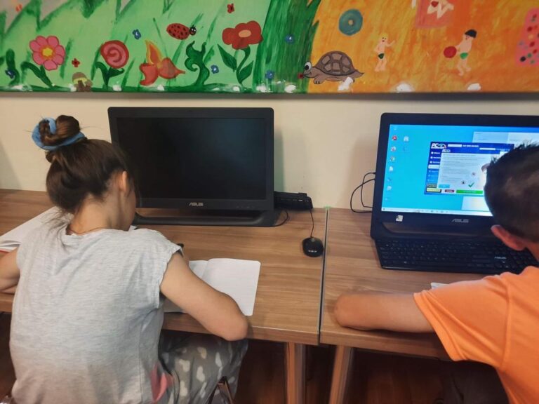 Dzieci siedzące przy biurko, odrabiają zadanie domowe.