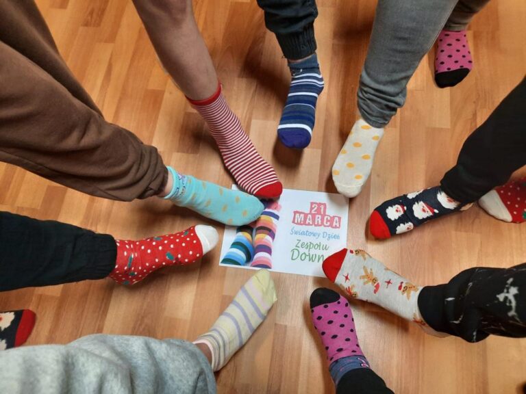 Zdjęcie nóg z kolorowymi skarpetkami dookoła kartki z napisem 21 marca Światowy Dzień Zespołu Downa