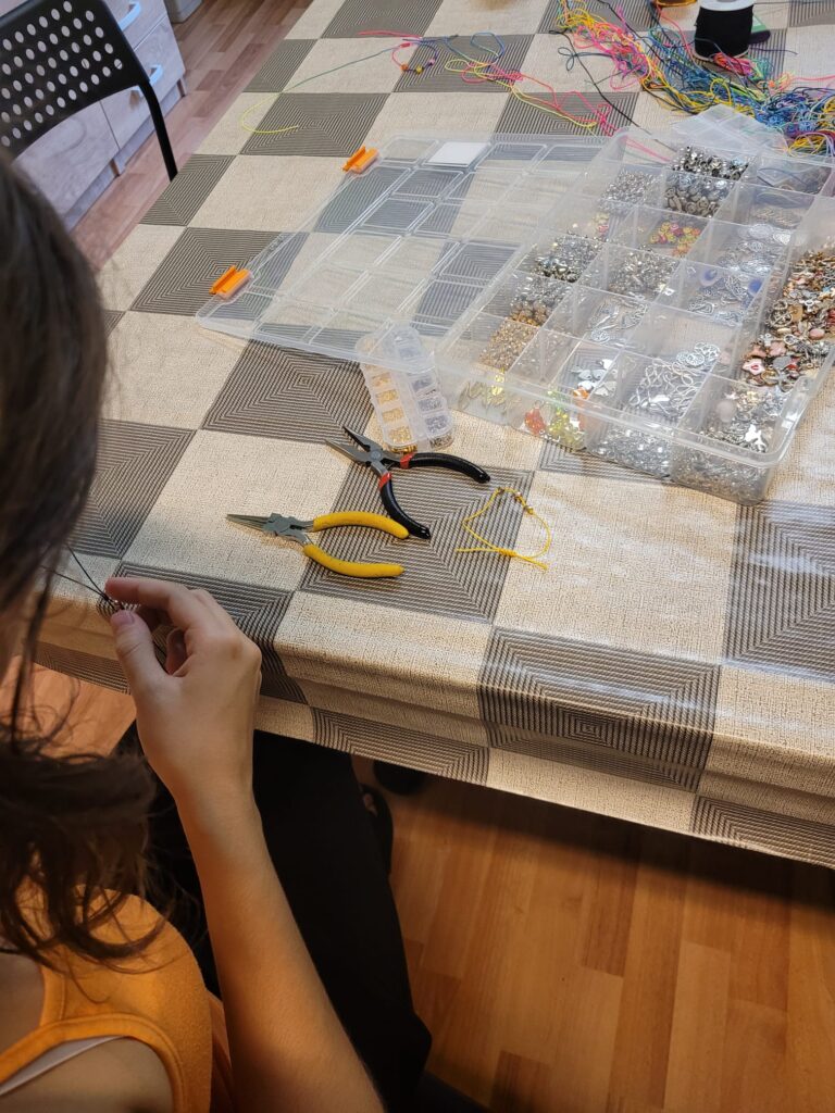 Dziewczynka podczas zajęć technicznych wykonująca bransoletkę z koralików.