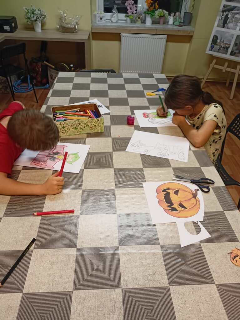 Chłopiec i dziewczynka wykonują prace plastyczne na Halloween.