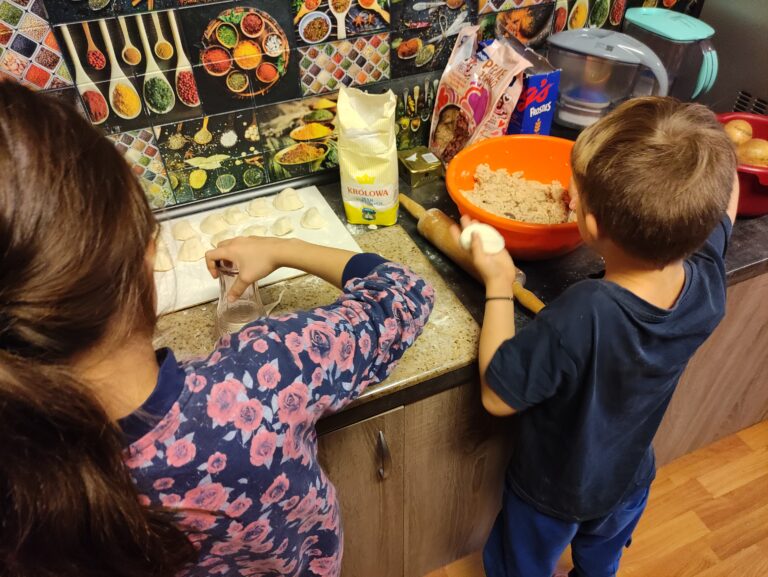 Chłopiec i dziewczynka lepią uszka na Boże Narodzenie.