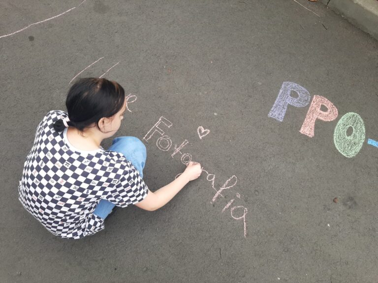 Dziewczyna rysuje kredą na podwórku.