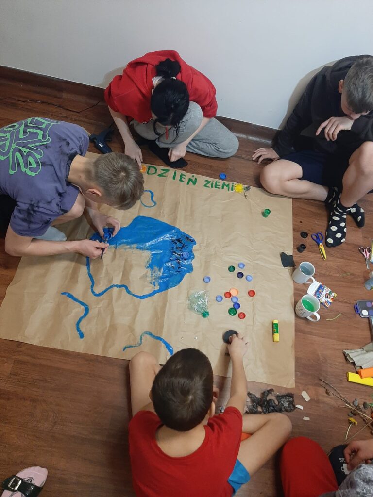 Wychowankowie przygotowują plakat w ramach Dnia Sprzątania Świata.