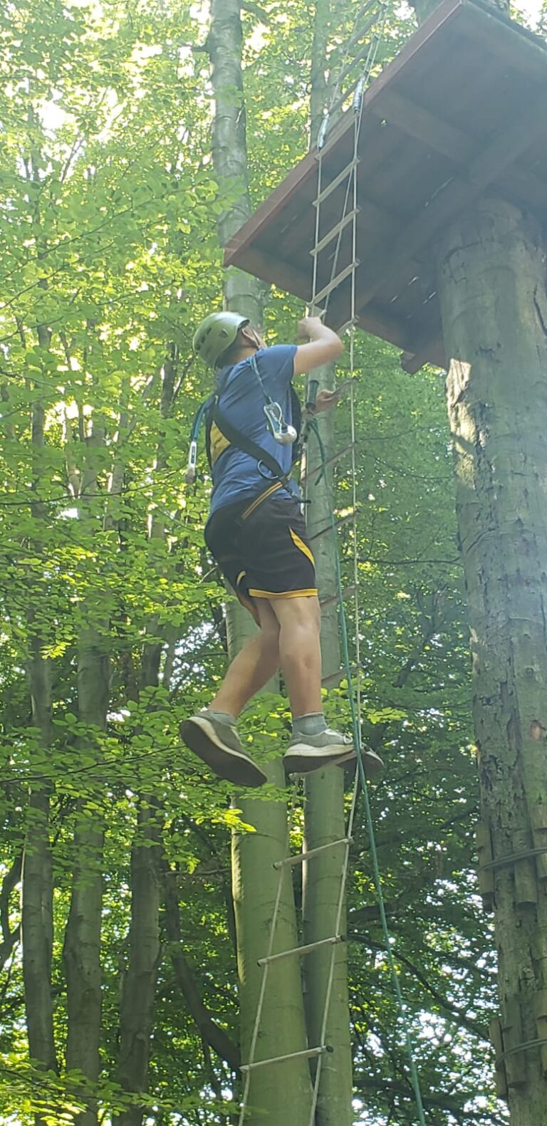 Chłopiec wspinający się na trasie w parku linowym.